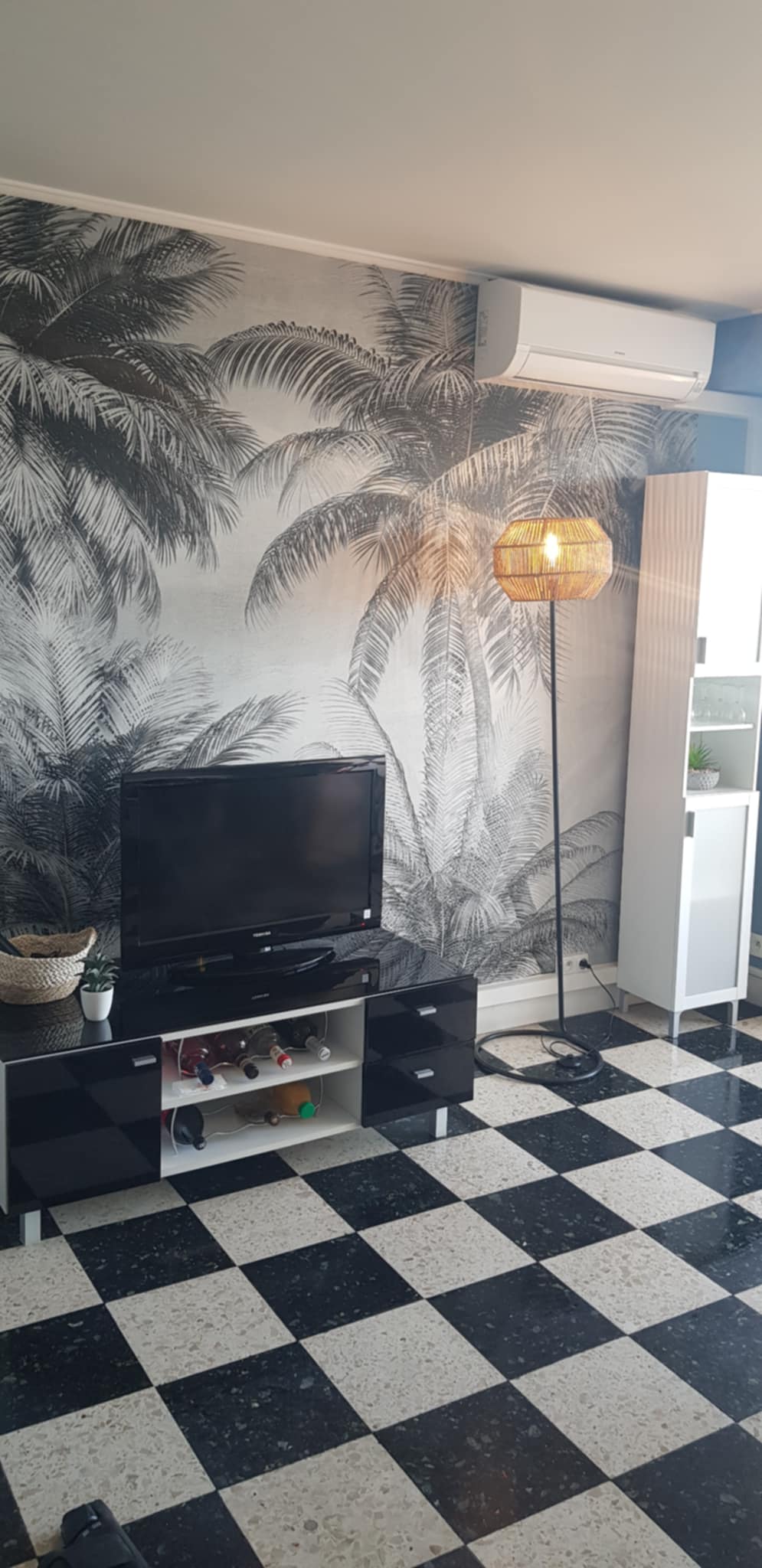 Salon avec papier peint tropical et espace TV